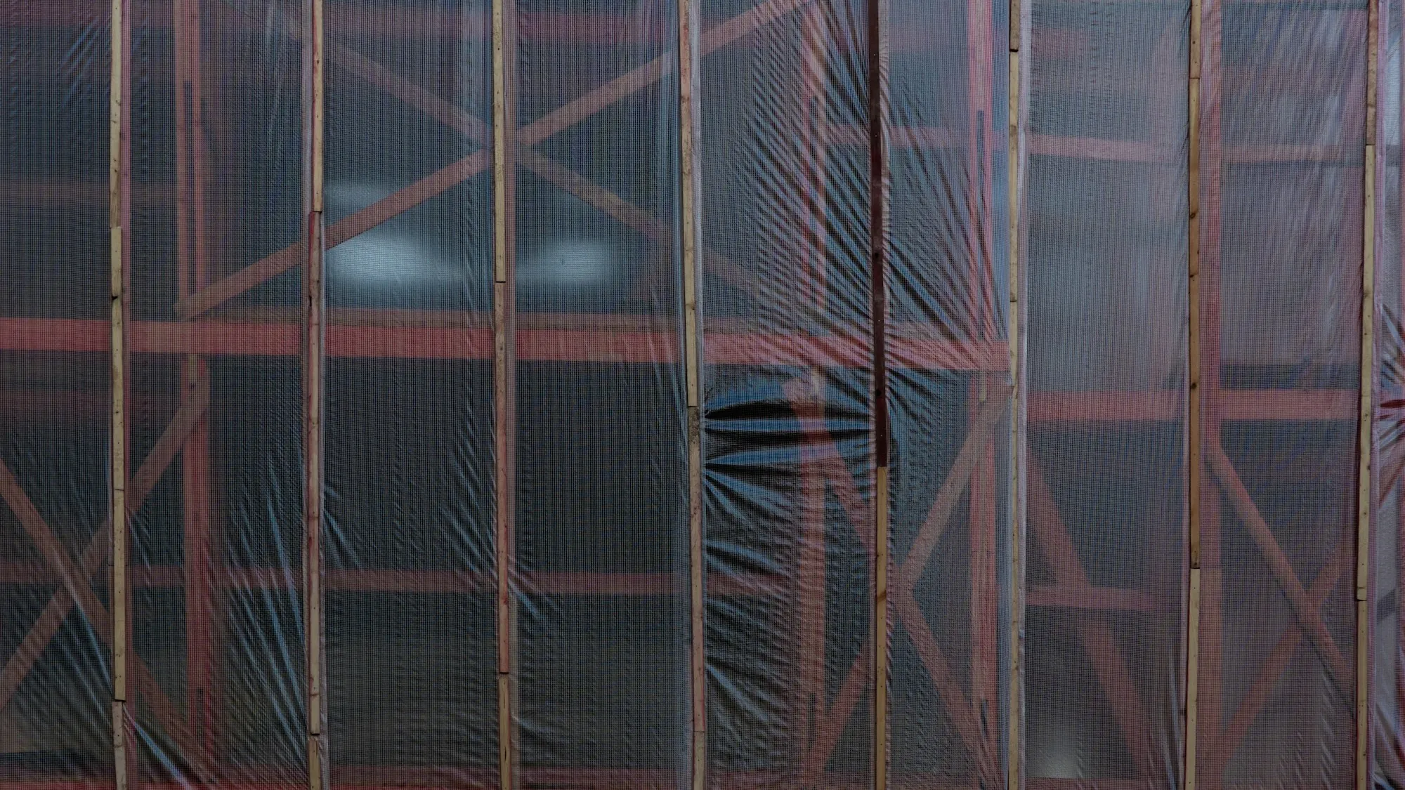 Building wrapped in plastic sheeting on scaffolding